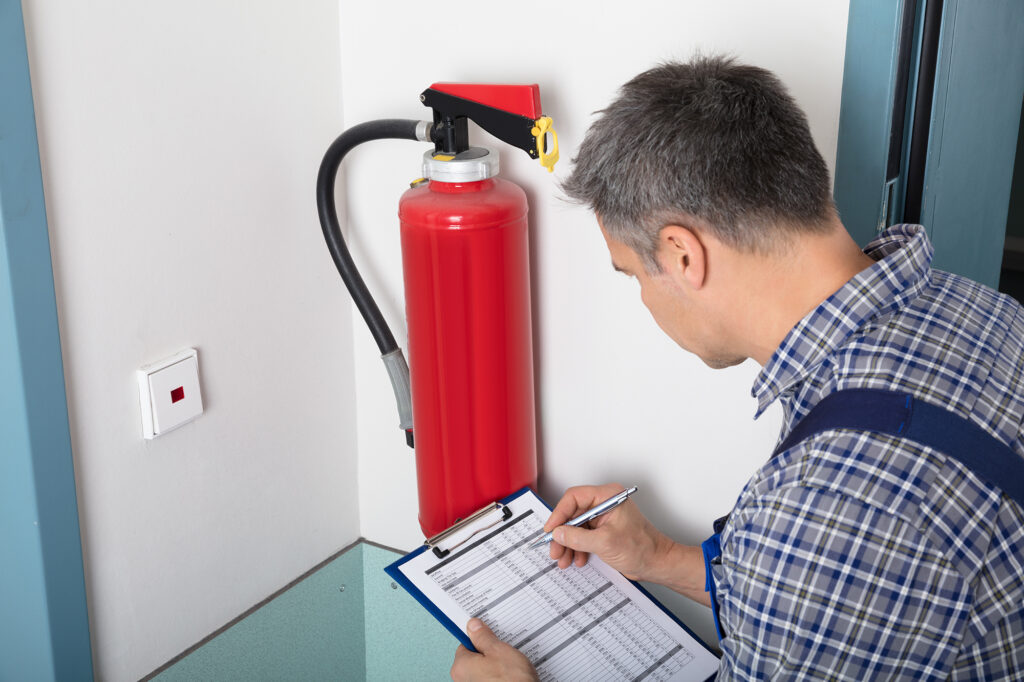 technician checking fire extinguisher, fire risk assessment